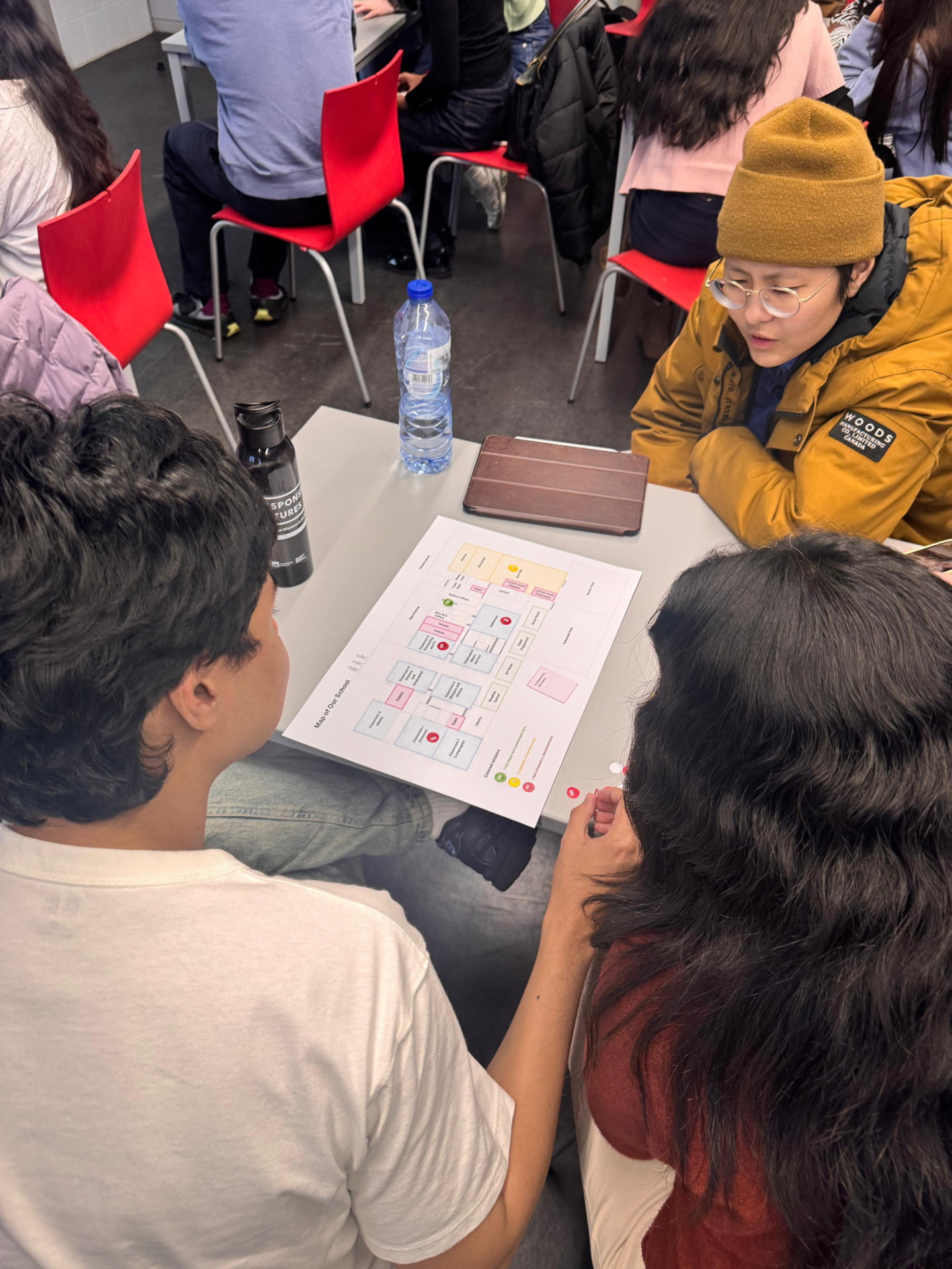 Players leaning over a printed floor plan, discussing sticker placement